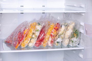 Plastic bags with deep frozen vegetables in refrigerator
