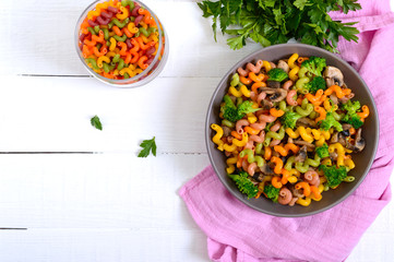 Cavatappi colored pasta with broccoli and mushrooms on a white wooden background. Pasta colorata. Pasta with vegetables. The top view