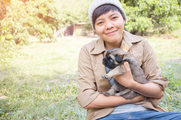 Obraz premium Happy Asian owner carrying, hugging Carrying three adorable puppies dog her sitting green grass backyard lawn