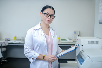 Dark-haired technician in eyewear reading test result