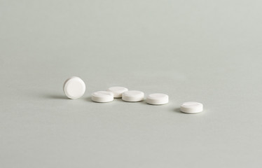 Isolated white tablets on grey background.