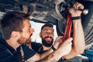 Two mechanics in uniform are working in auto service