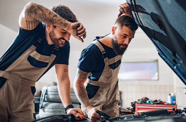 Two mechanics in uniform are working in auto service