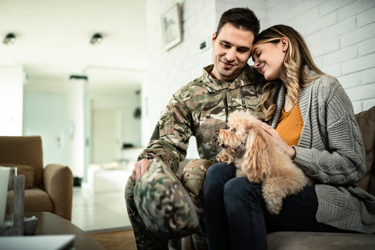 Happy military couple with dog sitting embraced at home.