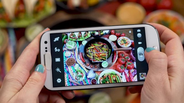 Hands Using Smartphone Taking Photos Traditional Mexican Food with a Smartphone Hot Fajitas is Served with Sauces and Tortilla and Vegetables, Burritos, Bean Soup with Chili