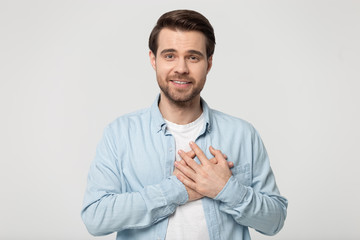 Grateful millennial guy folded hand on chest near heart.