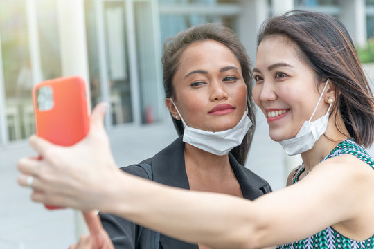 Couple of asian female friends enjoying outdoor time together wearing hygienic mask to prevent the virus PM2.5 and Coronavirus. Air pollution, Environmental awareness concept