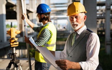 Male architects analyzing blueprint at construction site