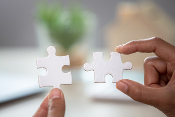 Business woman is trying to connect couple puzzle piece. Symbol of association and connection. Concept of business strategy