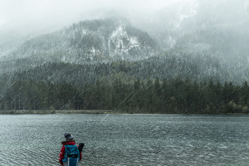 backpacker looks to the lake in the mountains of Bavaria, rainy day, Hintersee Ramsau