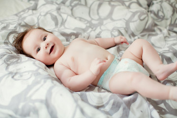 Cute baby boy in diaper lying on the bed