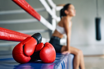 Red boxing gloves on boxing ring in gym - obrazy, fototapety, plakaty