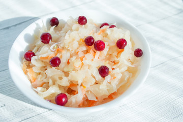 Sauerkraut with cranberries in a white cup, closeup. Probiotics food concept. Selective focus, copy space for text.