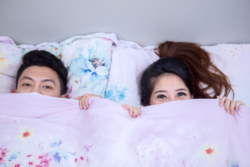 Young couple peeking with blanket