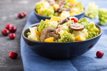 Vegetarian salad from romanesco cabbage, champignons, cranberry, avocado and pumpkin on a black concrete background. side view, selective focus.