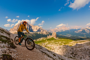 View of cyclist riding mountain bike on single trail in Dolomites, Cinque Torri, South Tirol, Italy