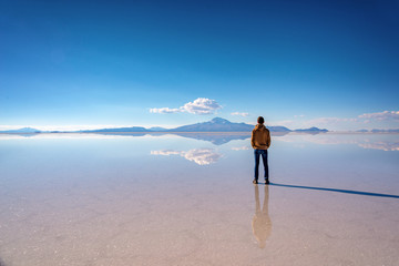 Young man watching the scenery and miror effect in Salar de Uyuni (Uyuni salt flats), Potosi, Bolivia, South America