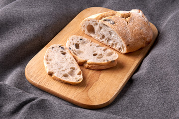 Ciabatta cut into slices on a wooden cutting board. Fresh diet homemade bread baked according to a traditional Italian recipe.