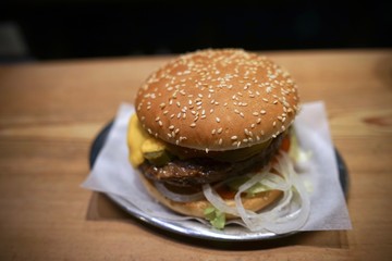 Cheeseburger with cheese, tomato, lettuce and onions on metal plate