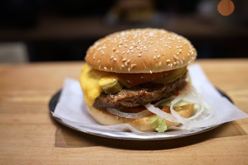 Cheeseburger with cheese, tomato, lettuce and onions on metal plate