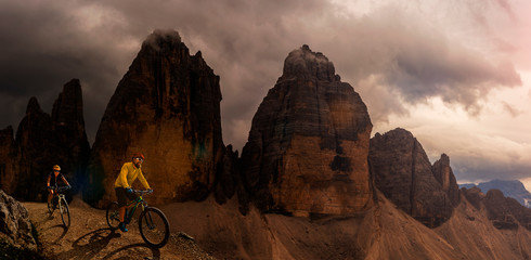Cycling outdoor adventure in Dolomites. Cycling woman and man  on electric mountain bikes in...
