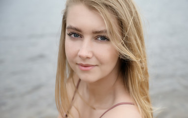 Young woman in pink dress on sand and enjoys sea.