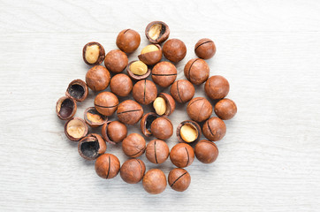Macadamia nut in bowl on white wooden background.