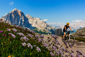 Cycling outdoor adventure in Dolomites. Cycling woman in Dolomites landscape. Woman cycling MTB...