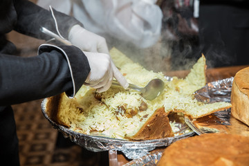 Khan pilaf in a pita. Traditional oriental dish on tableware Azerbaijan with fire on a table in restaurant .the chef cuts off the drill. Shah pilaf.