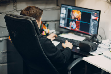 Young man sitting on chair with computer desktop near virtual reality goggles, vr glasses headset