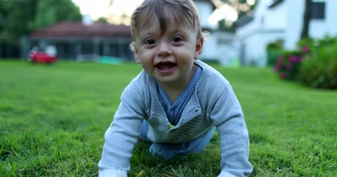 Baby turning around and crawling towards camera. Infant toddler in outdoor home garden