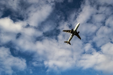 White airplane viewed from behind flying with a sky background with some white clouds