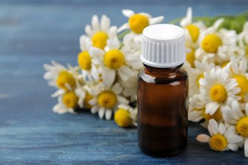 Medicinal chamomile and chamomile extract in a bottle. oil from chamomile flowers. aromatherapy. a drug. on a blue wooden table. close-up