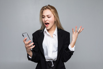 Surprised pretty businesswoman chatting by phone standing isolated over white background.