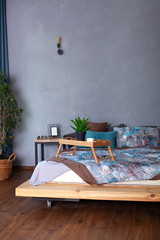 Wooden breakfast tray on bed in morning. cup of espresso in morning to bed. Honeymoon, surprise. interior dark bedroom. Room decor loft. Bedroom interior with a small table on bed and a cup of coffee
