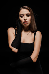 Naklejka premium attractive woman in gloves looking at camera isolated on black