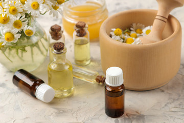 Fototapeta na wymiar Medicinal chamomile and chamomile extract in a bottle. oil from chamomile flowers. aromatherapy. a drug. on a light concrete table.