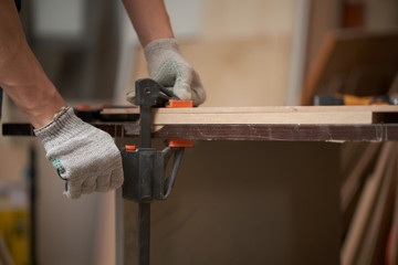 Man carpenter clamps board in vice in workshop
