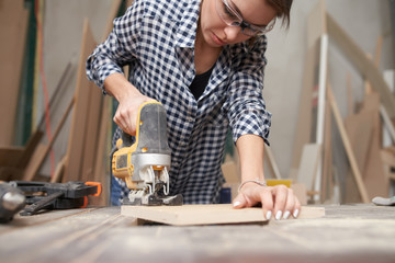 Fototapeta na wymiar Brunette woman carpenter working with fretsaw