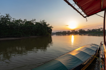 Amazon rainforest sunset during a boat trip with a reflection of the trees in the water. Puerto...