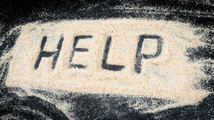 Top view of HELP word written on white sand