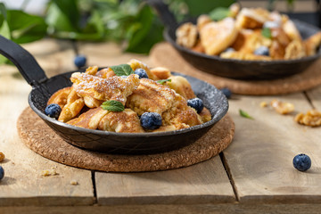 Kaiserschmarrn in a black pan on a wooden table and some decoration