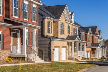 Fototapeta na wymiar Luxury single family homes covered with brick, or vinyl sidings, covered entrances, two car garage on a newly constructed high end residential community street in Maryland USA