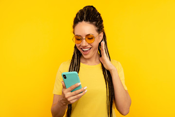 Pretty smiling young woman with dreadlocks posing with mobile isolated