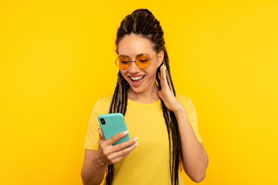 Pretty smiling young woman with dreadlocks posing with mobile isolated