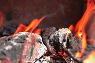 Piece of wood burning in fire lit by sunlight placed diagonally