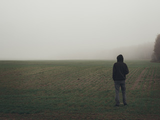 Obraz na płótnie Canvas Alone man stands in an empty misty field. Autumn misty landscapes