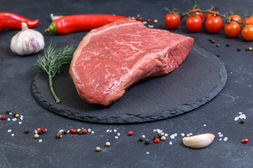 Raw fresh marbled meat and seasonings on dark background