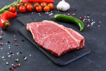 Raw fresh marbled meat and seasonings on dark background