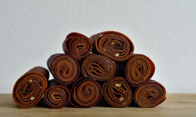 Sweet pureed fruit pastille.Fruit roll-ups homemade on a wooden background . Natural sweets from dried berries and fruits. healthy snack concept